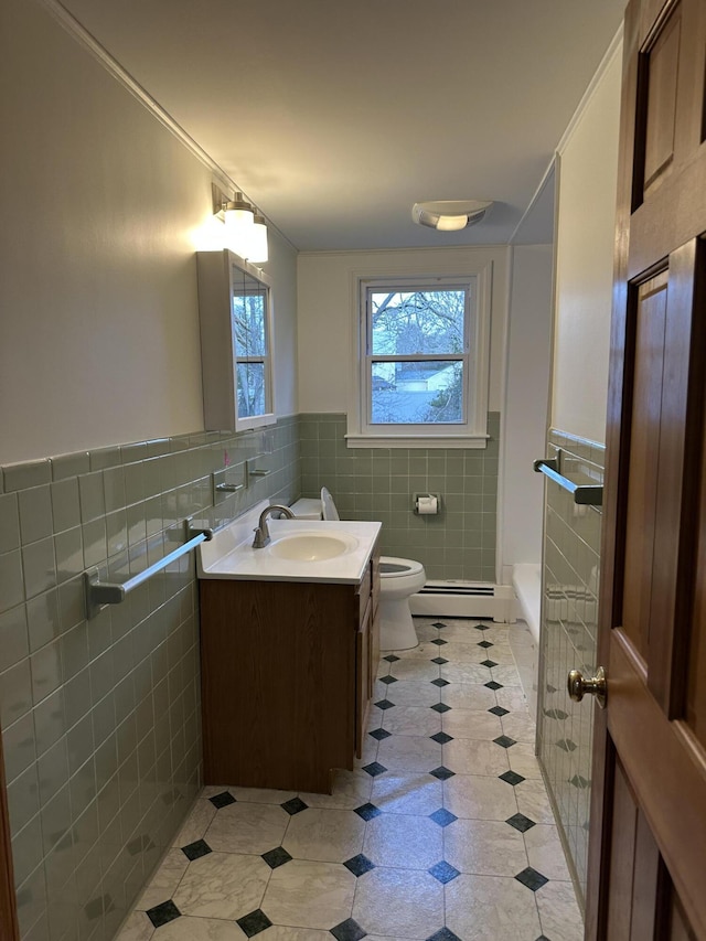 bathroom featuring toilet, a baseboard heating unit, tile walls, and vanity