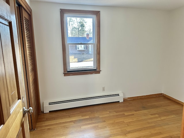 empty room featuring light wood finished floors and baseboard heating