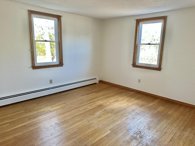 unfurnished room with a baseboard heating unit, a textured ceiling, light wood-style flooring, and baseboards