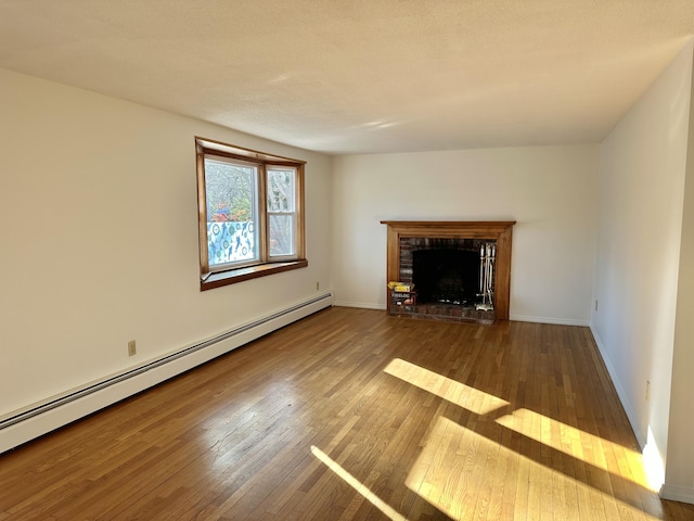 unfurnished living room featuring a baseboard radiator, wood-type flooring, a fireplace, and baseboards