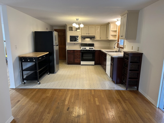 kitchen featuring range with gas cooktop, freestanding refrigerator, built in microwave, under cabinet range hood, and a sink