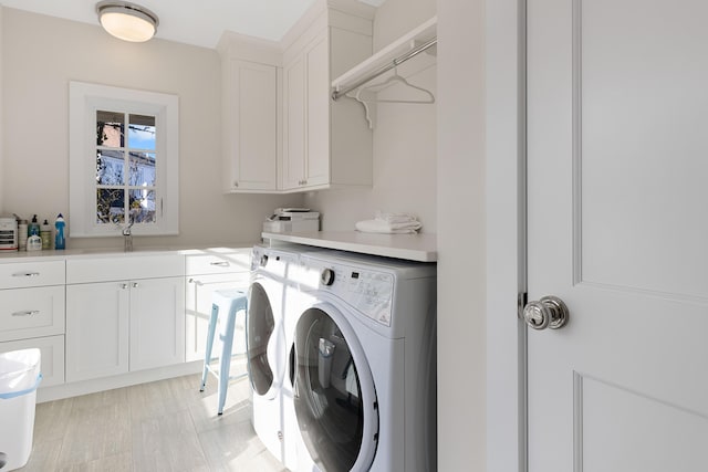 washroom featuring a sink, washing machine and clothes dryer, and cabinet space