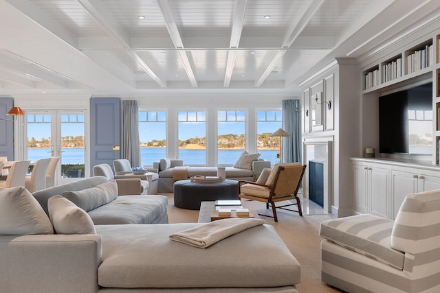 living room with a water view, a premium fireplace, beam ceiling, and french doors