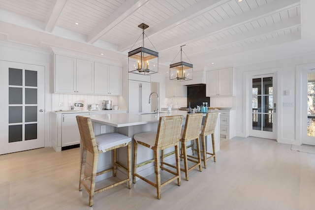 kitchen with a kitchen breakfast bar, white cabinets, light countertops, and light wood finished floors