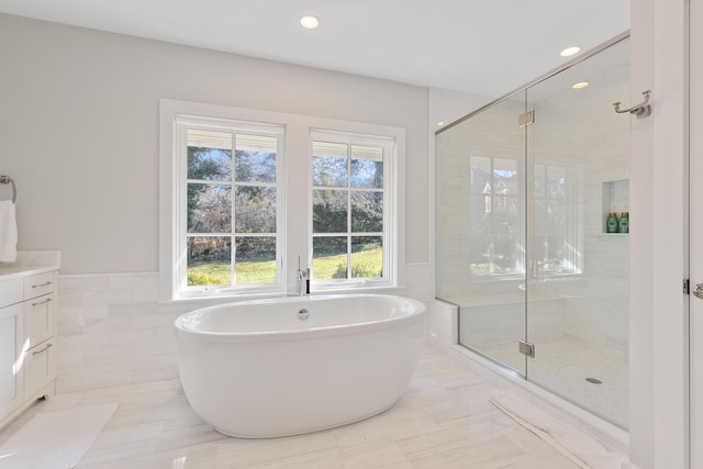 full bath featuring a wainscoted wall, a shower stall, a freestanding bath, and vanity