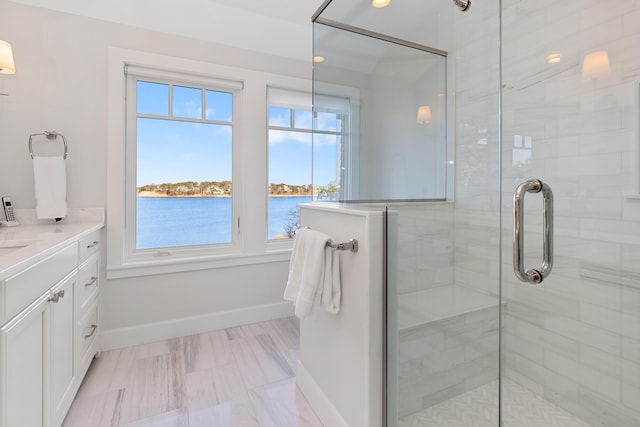 bathroom featuring a stall shower, a water view, and baseboards