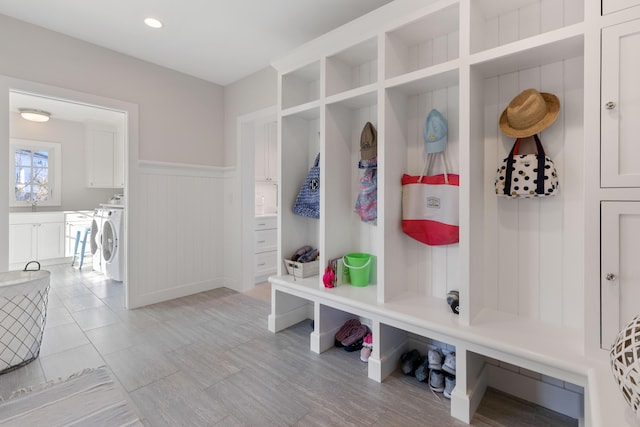 mudroom with washing machine and dryer, a wainscoted wall, a sink, and recessed lighting