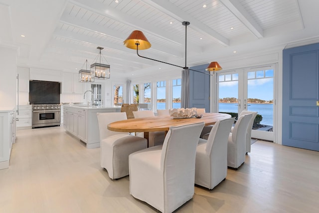 dining room featuring a water view, light wood-style floors, a wealth of natural light, and french doors