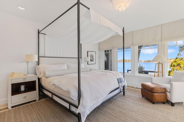 bedroom with lofted ceiling, a water view, and baseboards