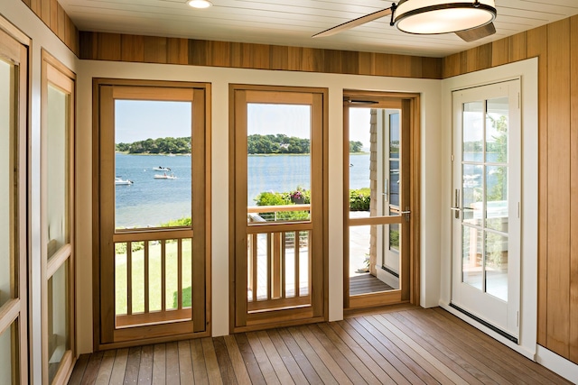 doorway featuring light wood finished floors, wood walls, and a water view