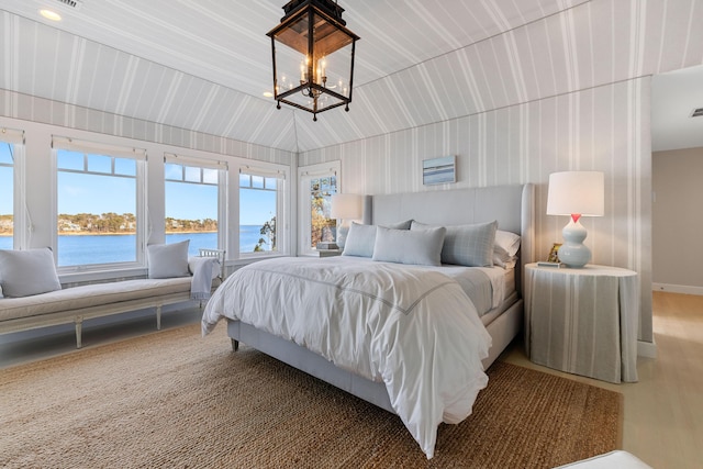 bedroom with lofted ceiling, a water view, and an inviting chandelier