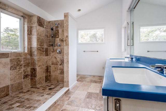 bathroom with lofted ceiling, vanity, and tiled shower