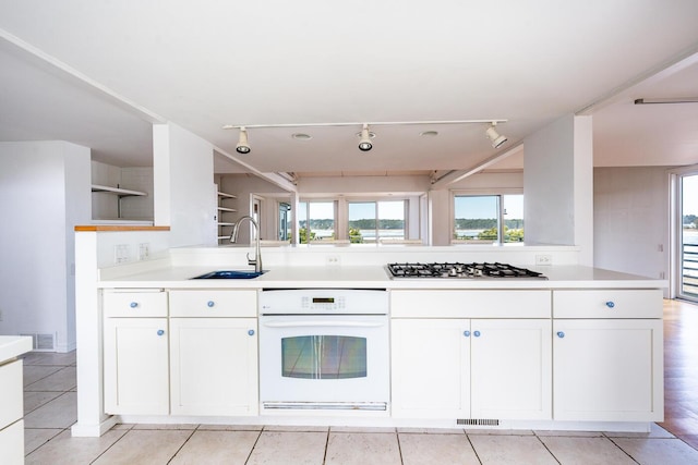 kitchen featuring stainless steel gas stovetop, sink, white oven, and white cabinets