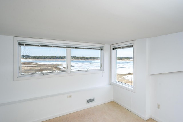 carpeted empty room featuring a water view