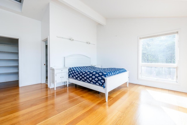 bedroom with multiple windows, lofted ceiling with beams, and hardwood / wood-style floors