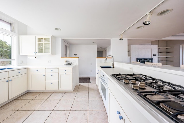 kitchen featuring white cabinetry, sink, stainless steel gas stovetop, and light tile patterned flooring