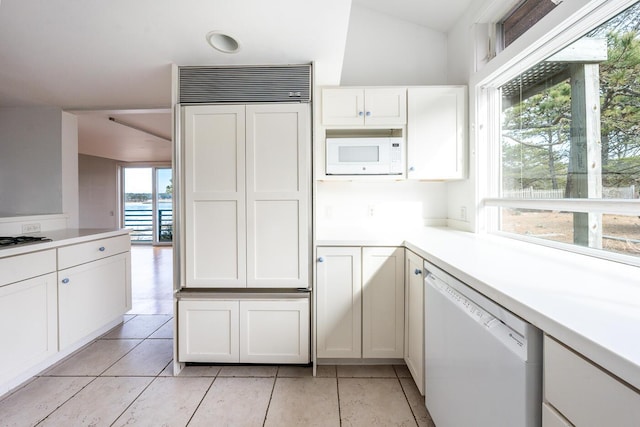 kitchen featuring built in appliances, white cabinetry, and a healthy amount of sunlight