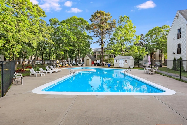 view of swimming pool with a patio area and a storage shed