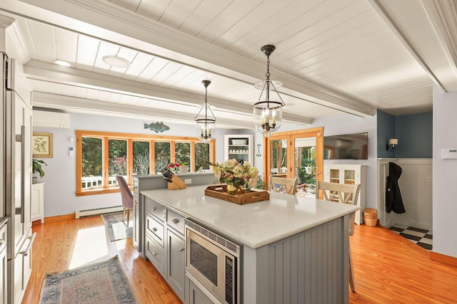 kitchen with pendant lighting, gray cabinets, stainless steel microwave, a baseboard radiator, and light wood-type flooring