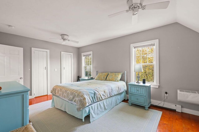 bedroom with multiple closets, hardwood / wood-style flooring, ceiling fan, and baseboard heating