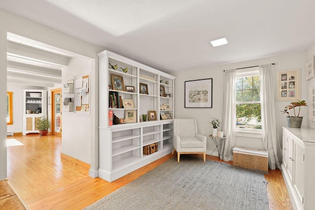 sitting room featuring beam ceiling, a baseboard radiator, and light wood-type flooring