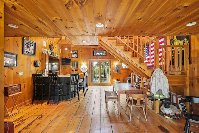 dining room with wood walls, wood-type flooring, bar, and wooden ceiling