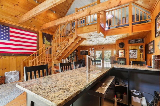 kitchen featuring wood ceiling, light hardwood / wood-style flooring, beam ceiling, light stone countertops, and wood walls