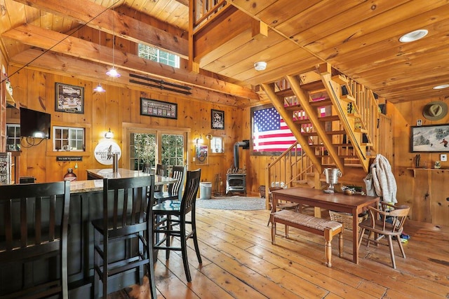 dining space with a wood stove, wood ceiling, light hardwood / wood-style floors, and wood walls