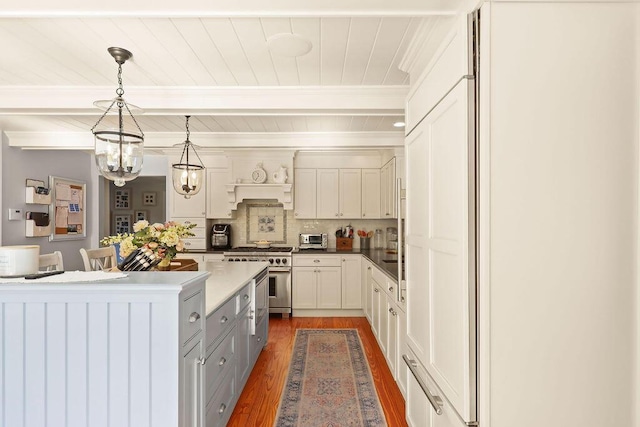 kitchen with hanging light fixtures, dark hardwood / wood-style floors, stainless steel range, white cabinets, and decorative backsplash