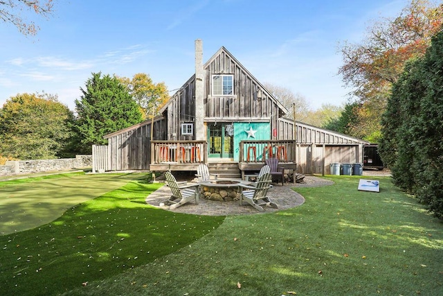 back of house with a yard, a deck, and a fire pit