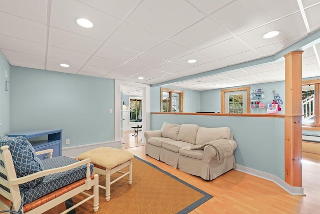 living room with baseboard heating, hardwood / wood-style floors, and a drop ceiling