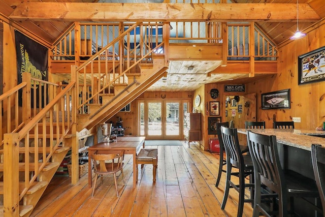 dining area featuring wooden walls, lofted ceiling with beams, wood-type flooring, wooden ceiling, and french doors