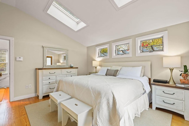 bedroom with lofted ceiling with skylight and light wood-type flooring