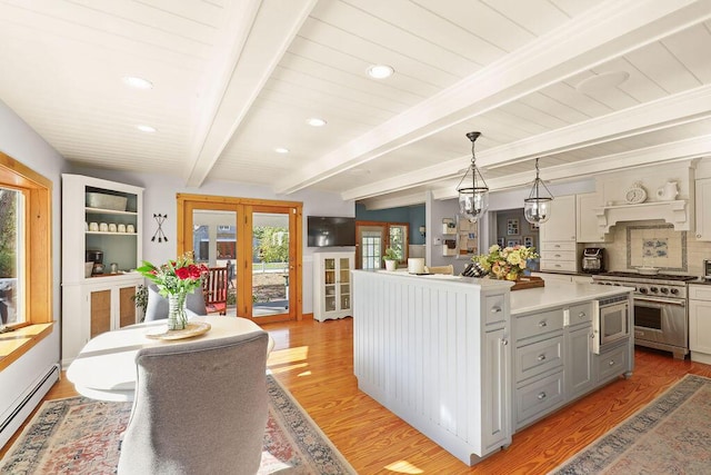 kitchen with beamed ceiling, a baseboard radiator, hanging light fixtures, stainless steel appliances, and french doors