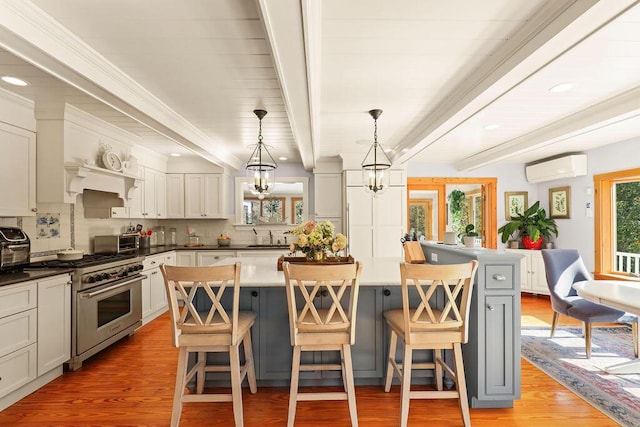 kitchen with a kitchen bar, decorative light fixtures, a center island, and high end stove