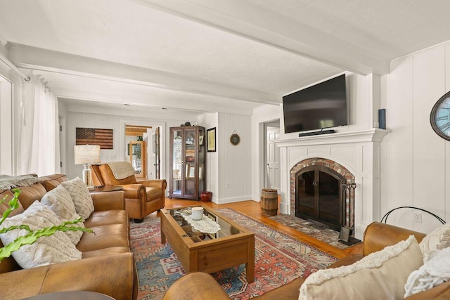 living room with a fireplace, beam ceiling, and light hardwood / wood-style flooring