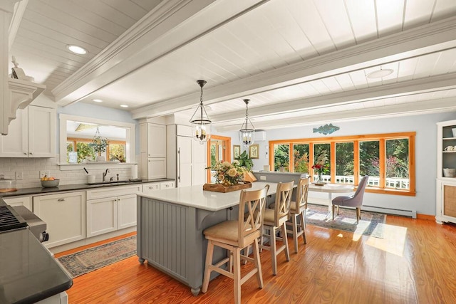 kitchen with white cabinetry, hanging light fixtures, a kitchen breakfast bar, a center island, and beamed ceiling