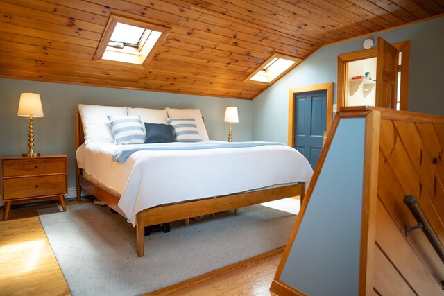 bedroom featuring a skylight, vaulted ceiling, wood finished floors, and wooden ceiling