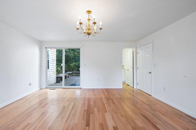 spare room with light wood-type flooring and an inviting chandelier