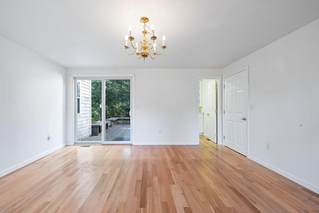 spare room with light wood-type flooring and an inviting chandelier
