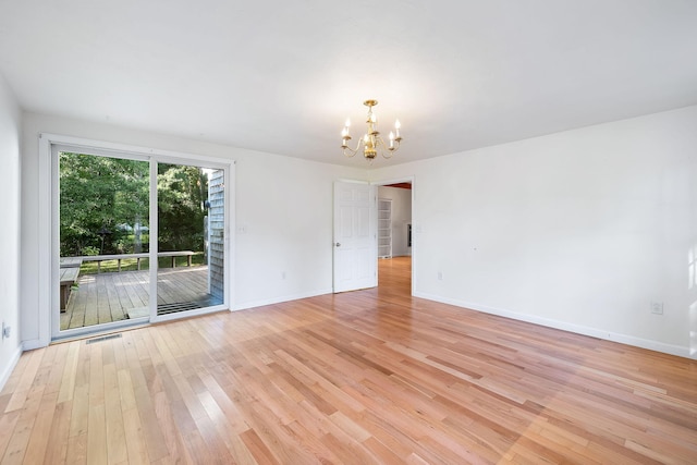 empty room with a chandelier and light hardwood / wood-style floors