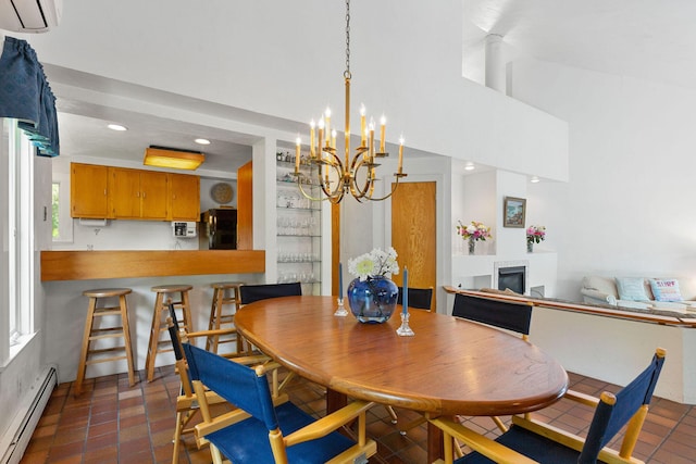 24 Sparrowhawk Rd, Orleans, MA 02653 - dining space with a baseboard radiator, a glass covered fireplace, a chandelier, a wall unit AC, and a high ceiling