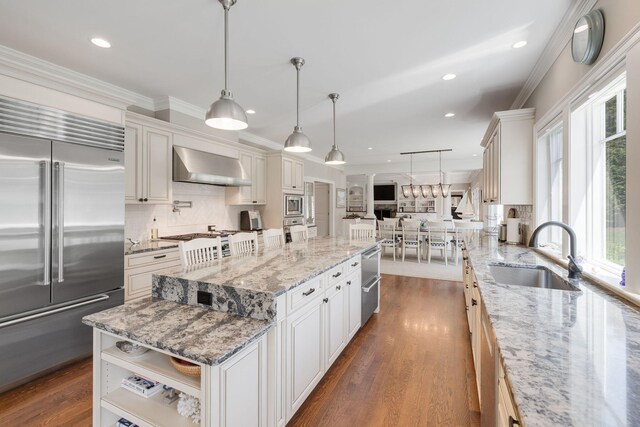 10 Shiverick Rd, East Dennis, MA 02641 - kitchen with built in appliances, wall chimney range hood, open floor plan, backsplash, and dark wood finished floors