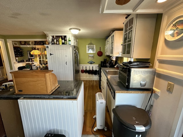 kitchen featuring dark wood-type flooring, sink, a textured ceiling, and stainless steel fridge