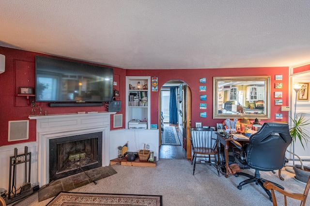 living room featuring carpet floors, a textured ceiling, and built in shelves