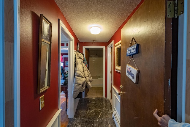 hall featuring baseboard heating and a textured ceiling