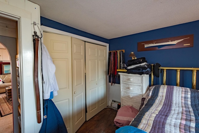 bedroom with dark wood-type flooring, a textured ceiling, a closet, and a baseboard heating unit