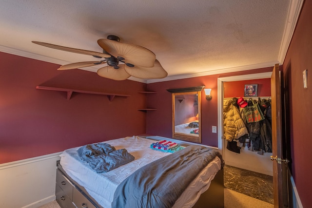 carpeted bedroom featuring a textured ceiling, a closet, ceiling fan, and ornamental molding