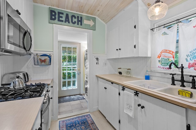 1205 Massasoit Rd, Eastham, MA 02642 - kitchen with stainless steel microwave, gas stove, light countertops, white cabinets, and wooden ceiling