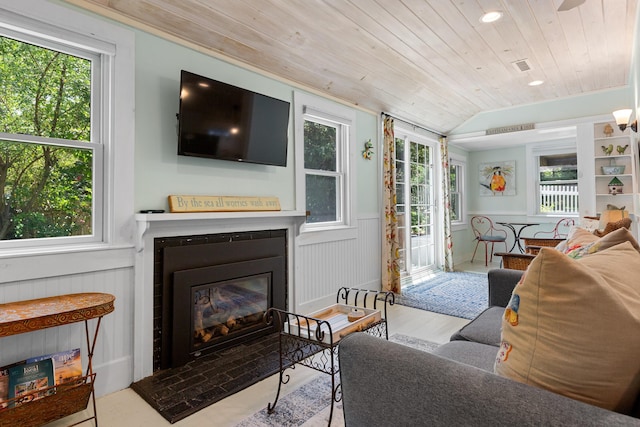 1205 Massasoit Rd, Eastham, MA 02642 - living area with a glass covered fireplace, wood finished floors, wood ceiling, a wainscoted wall, and vaulted ceiling